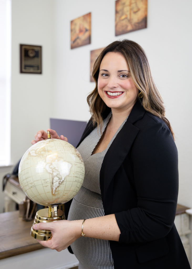 Georgetown Immigration Lawyer Ashleigh Hutchens in her office holding a globe wearing a black suit