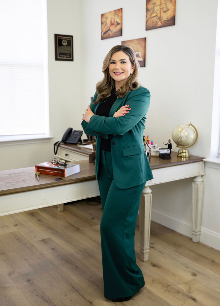 Immigration lawyer in Cedar Park Georgia Santos Laurent standing in front of desk in green suit